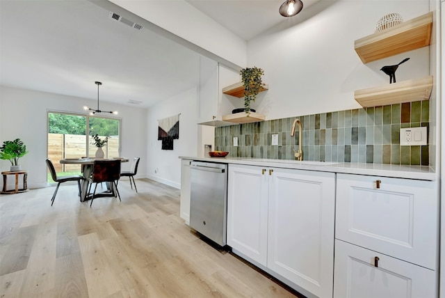 kitchen featuring decorative light fixtures, backsplash, stainless steel dishwasher, white cabinetry, and light wood-type flooring