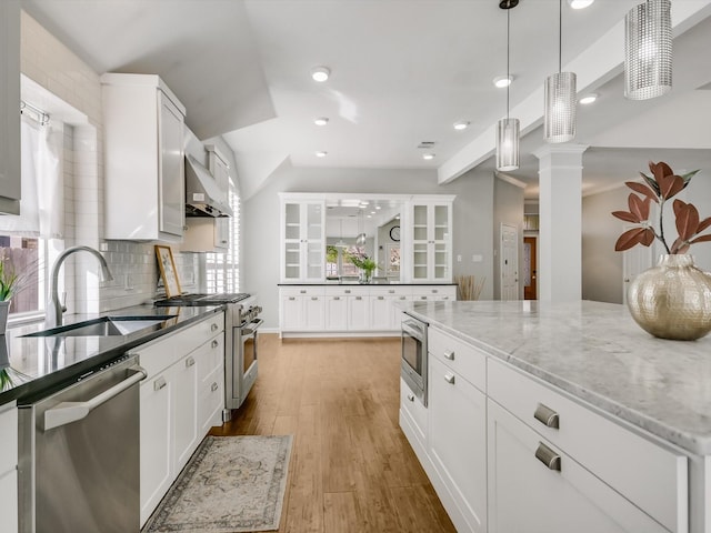 kitchen featuring light stone countertops, white cabinetry, stainless steel appliances, sink, and backsplash