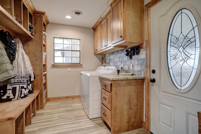 washroom featuring washing machine and dryer, light hardwood / wood-style floors, and cabinets