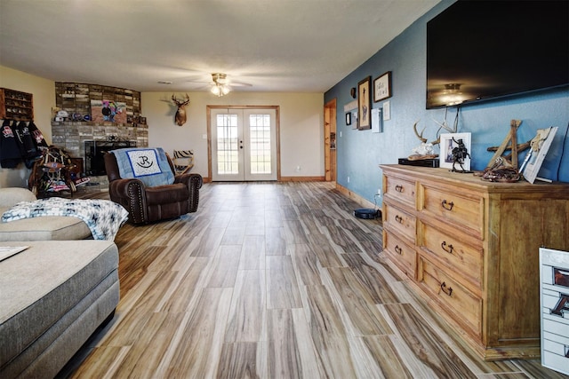 living room featuring ceiling fan, french doors, a brick fireplace, and hardwood / wood-style floors