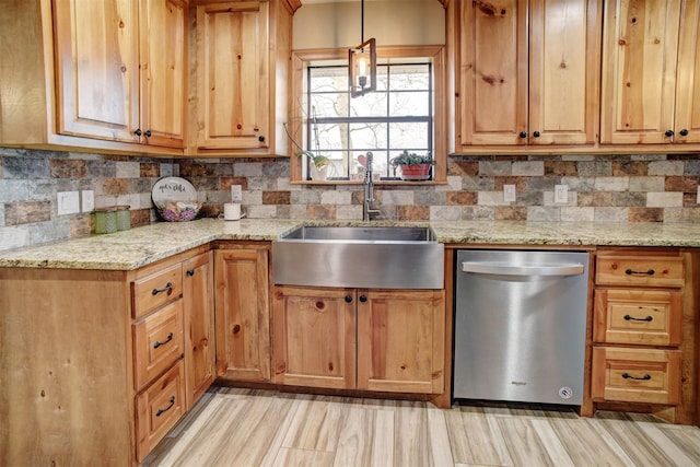 kitchen with decorative light fixtures, sink, light stone counters, and stainless steel dishwasher