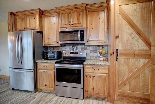 kitchen with decorative backsplash, light stone countertops, stainless steel appliances, and light hardwood / wood-style floors