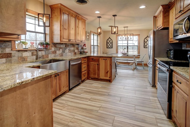 kitchen featuring decorative light fixtures, kitchen peninsula, sink, a breakfast bar area, and stainless steel appliances