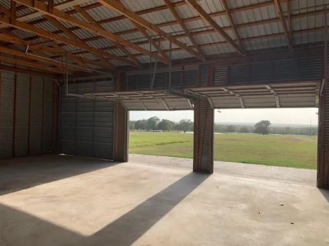 garage with a rural view and a lawn