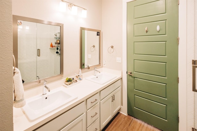 bathroom with a shower with shower door, hardwood / wood-style floors, and vanity