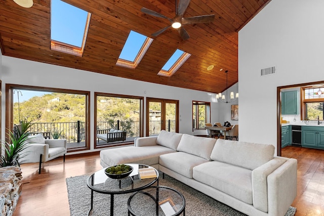 living room featuring wood ceiling, a skylight, an inviting chandelier, light hardwood / wood-style floors, and high vaulted ceiling