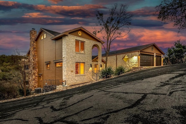112 Center Cove Iii Loop, Spicewood, TX 78669 - view of front of home with stone siding, a chimney, driveway, and a garage