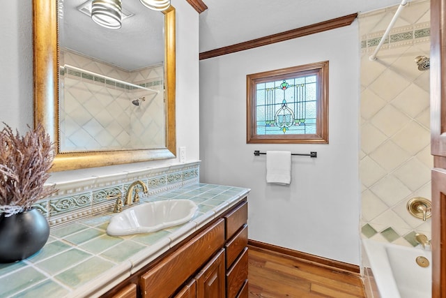 bathroom featuring hardwood / wood-style flooring, tiled shower / bath combo, vanity, and crown molding