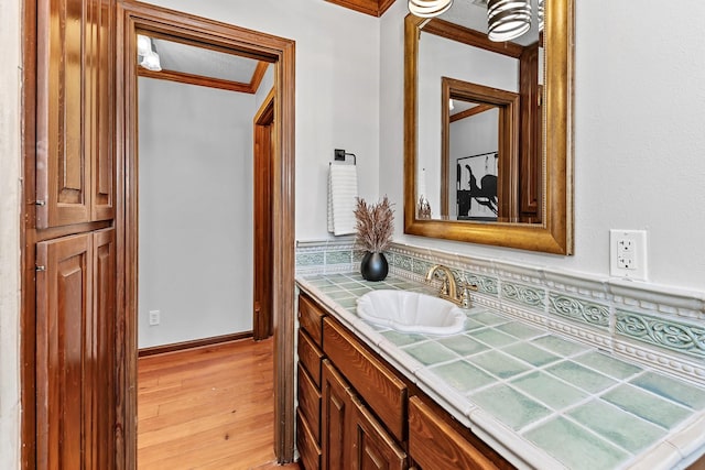 bathroom with decorative backsplash, hardwood / wood-style floors, vanity, and crown molding