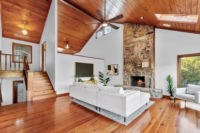 living room featuring a skylight, wood ceiling, a fireplace, high vaulted ceiling, and light hardwood / wood-style flooring