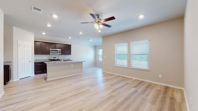 kitchen with ceiling fan, appliances with stainless steel finishes, light hardwood / wood-style flooring, and a kitchen island with sink