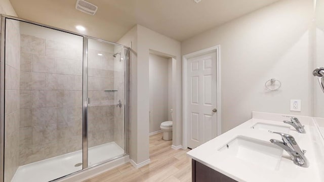 bathroom with hardwood / wood-style floors, toilet, a shower with door, and vanity