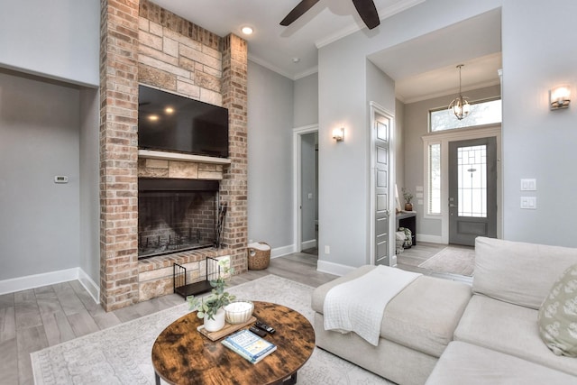 living room featuring ceiling fan, light hardwood / wood-style flooring, crown molding, and a fireplace