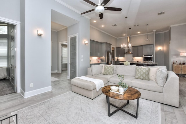 living room featuring ceiling fan with notable chandelier, light hardwood / wood-style flooring, and ornamental molding