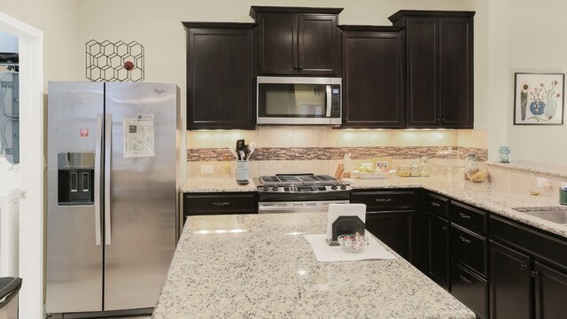 kitchen featuring appliances with stainless steel finishes, backsplash, and light stone counters