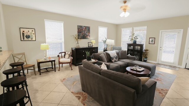 living area with light tile patterned floors, a ceiling fan, and baseboards