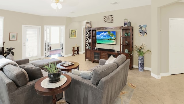 living area featuring baseboards, visible vents, a ceiling fan, and light tile patterned flooring