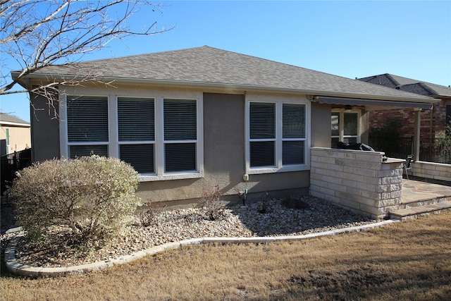 rear view of house featuring a patio area, a shingled roof, exterior kitchen, and stucco siding