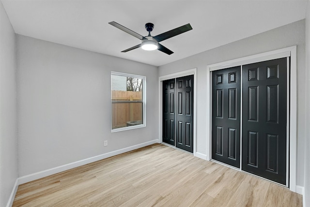 unfurnished bedroom featuring ceiling fan, two closets, and light wood-type flooring