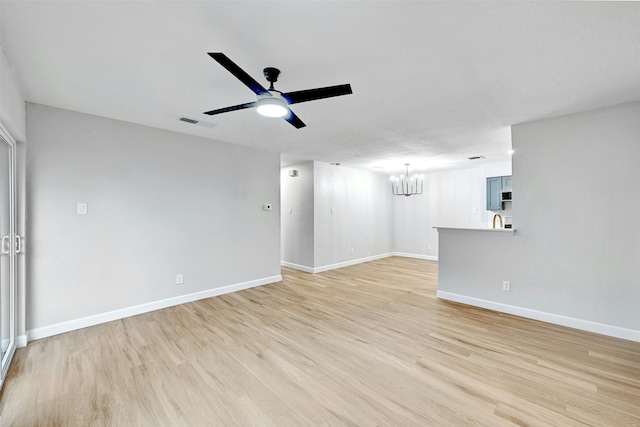 unfurnished living room with sink, ceiling fan with notable chandelier, and light hardwood / wood-style flooring