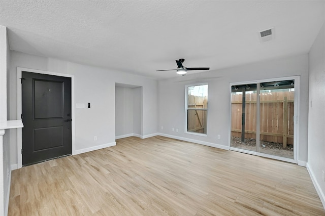 spare room with light wood-type flooring, ceiling fan, and a textured ceiling