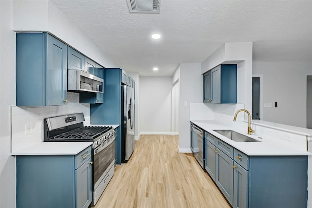 kitchen with sink, tasteful backsplash, a textured ceiling, and stainless steel appliances