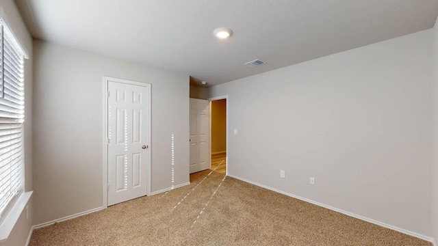 unfurnished bedroom featuring light colored carpet and a closet