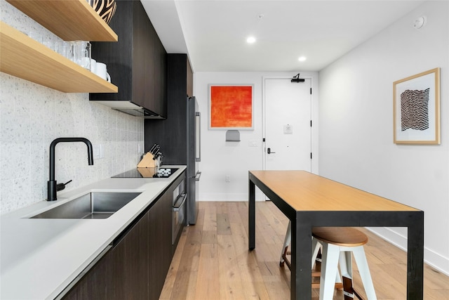 kitchen featuring stainless steel fridge, sink, tasteful backsplash, black electric cooktop, and light hardwood / wood-style floors