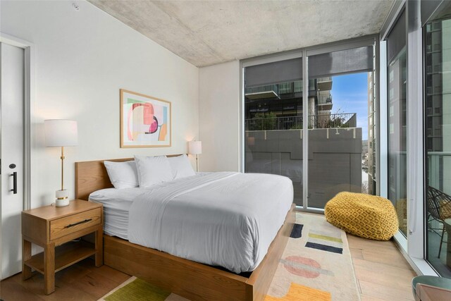 bedroom featuring wood-type flooring, expansive windows, and access to outside