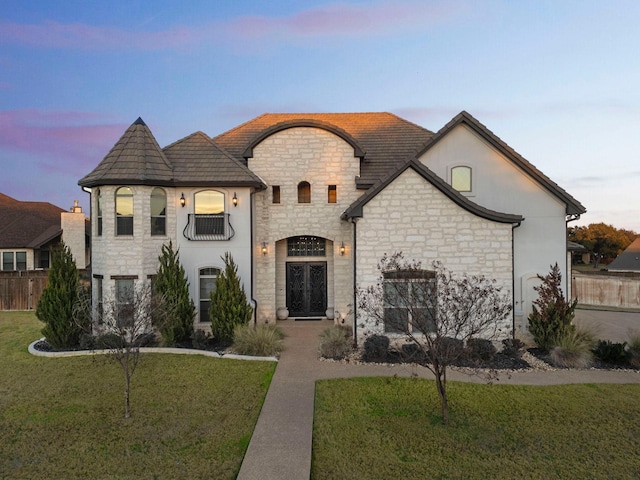 french provincial home featuring a balcony and a yard