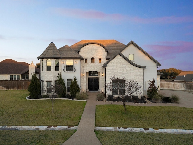 french provincial home with a lawn