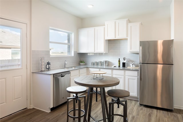 kitchen featuring appliances with stainless steel finishes, sink, backsplash, white cabinets, and light wood-type flooring