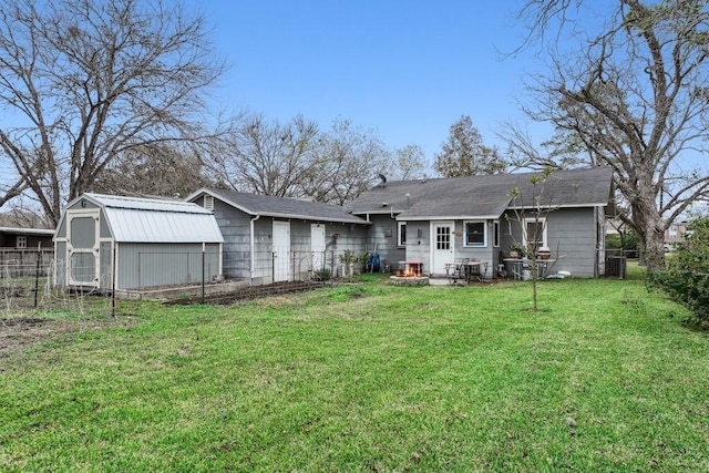 rear view of house with a lawn and a storage shed