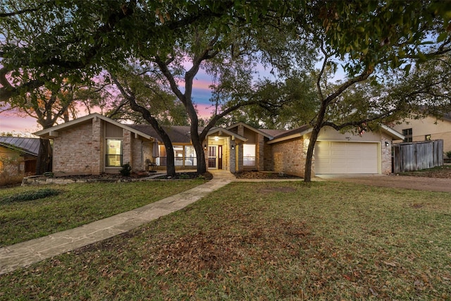 ranch-style home with a garage and a lawn