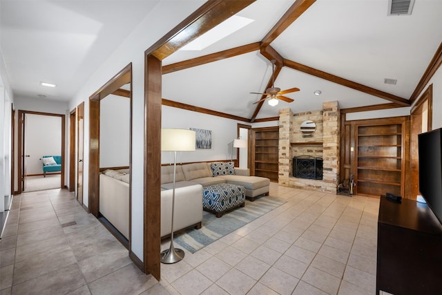 living room featuring built in shelves, lofted ceiling with skylight, a fireplace, and light tile patterned flooring