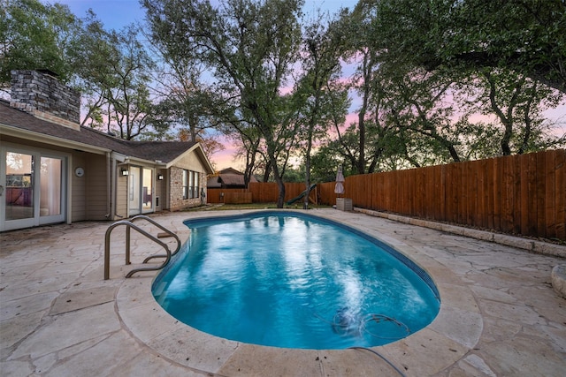 pool at dusk with a patio area