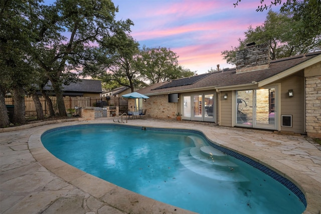 pool at dusk with a patio and french doors