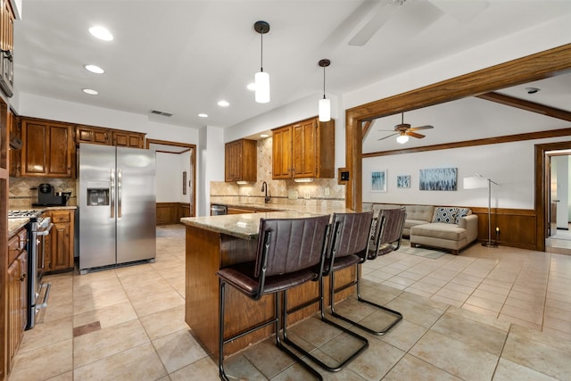 kitchen featuring sink, kitchen peninsula, a breakfast bar, stainless steel appliances, and light stone counters