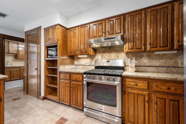 kitchen featuring light stone countertops, stainless steel range with gas cooktop, light tile patterned floors, and tasteful backsplash