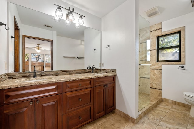 bathroom with a tile shower, a healthy amount of sunlight, toilet, and vanity