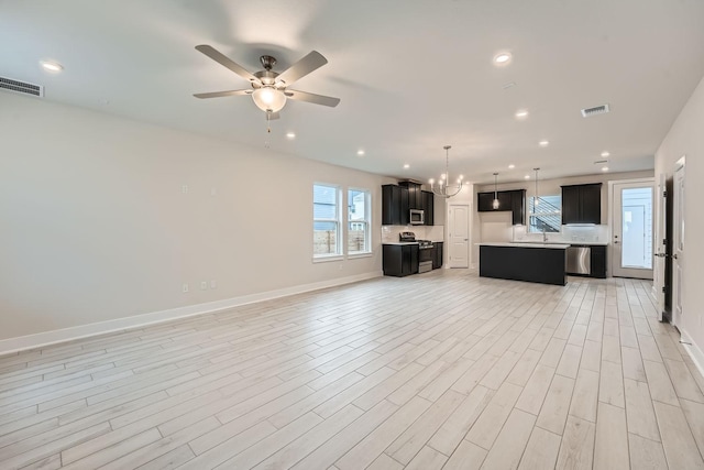 unfurnished living room featuring ceiling fan with notable chandelier and light hardwood / wood-style flooring