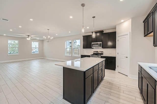 kitchen with decorative backsplash, hanging light fixtures, stainless steel appliances, and a kitchen island