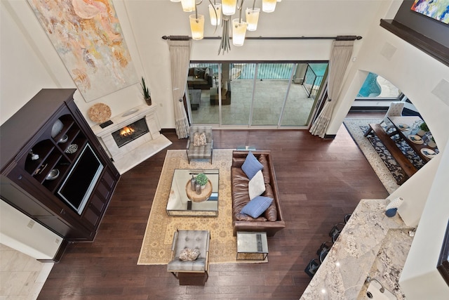 living room featuring a towering ceiling, dark hardwood / wood-style flooring, a notable chandelier, and a fireplace