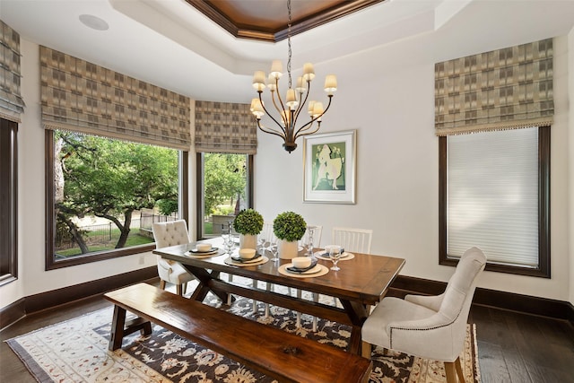 dining room featuring dark hardwood / wood-style flooring, a chandelier, a tray ceiling, and ornamental molding