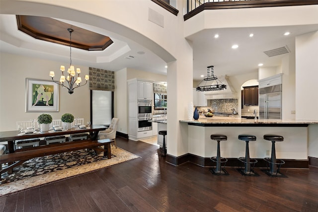 kitchen featuring a kitchen breakfast bar, dark hardwood / wood-style flooring, white cabinets, a tray ceiling, and stainless steel appliances