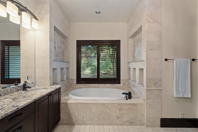 bathroom with vanity and tiled bath