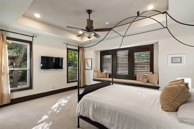 bedroom with ceiling fan, carpet flooring, and a tray ceiling