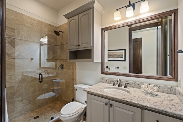 bathroom with a shower with shower door, toilet, and vanity