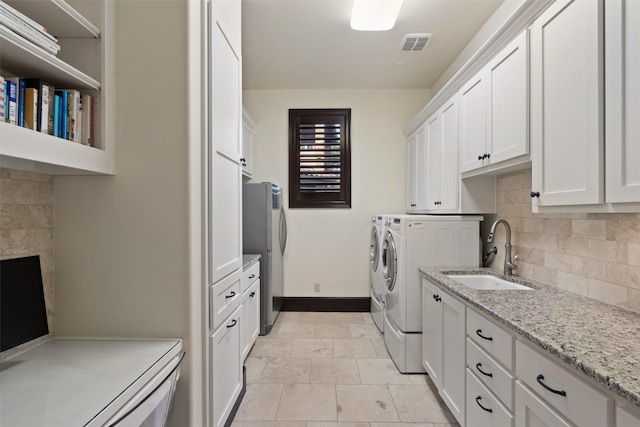 clothes washing area with sink, cabinets, and washing machine and dryer