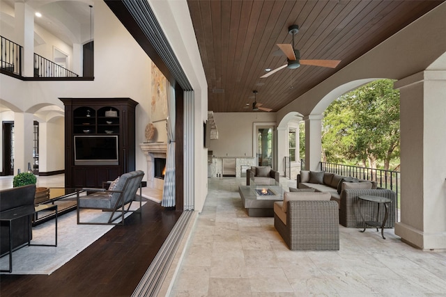 view of patio with an outdoor living space with a fireplace and ceiling fan